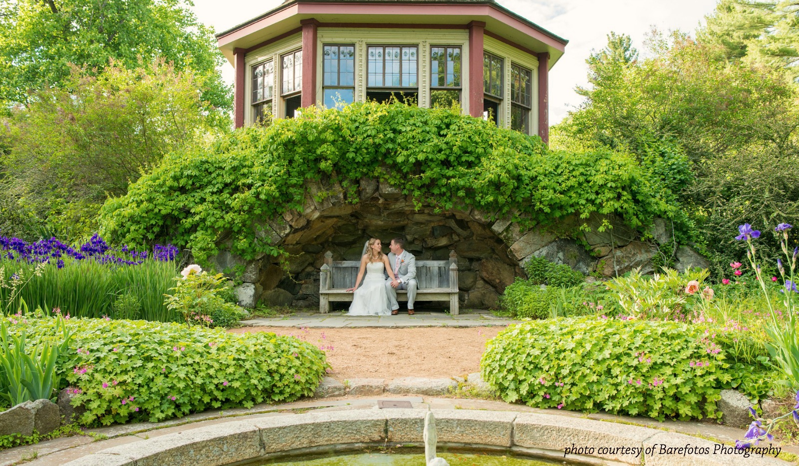 Bride and groom posing for portrait in formal garden below tea house